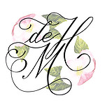 The de Havilland Memories logo with "de H M" in writing, in front of apple blossom.